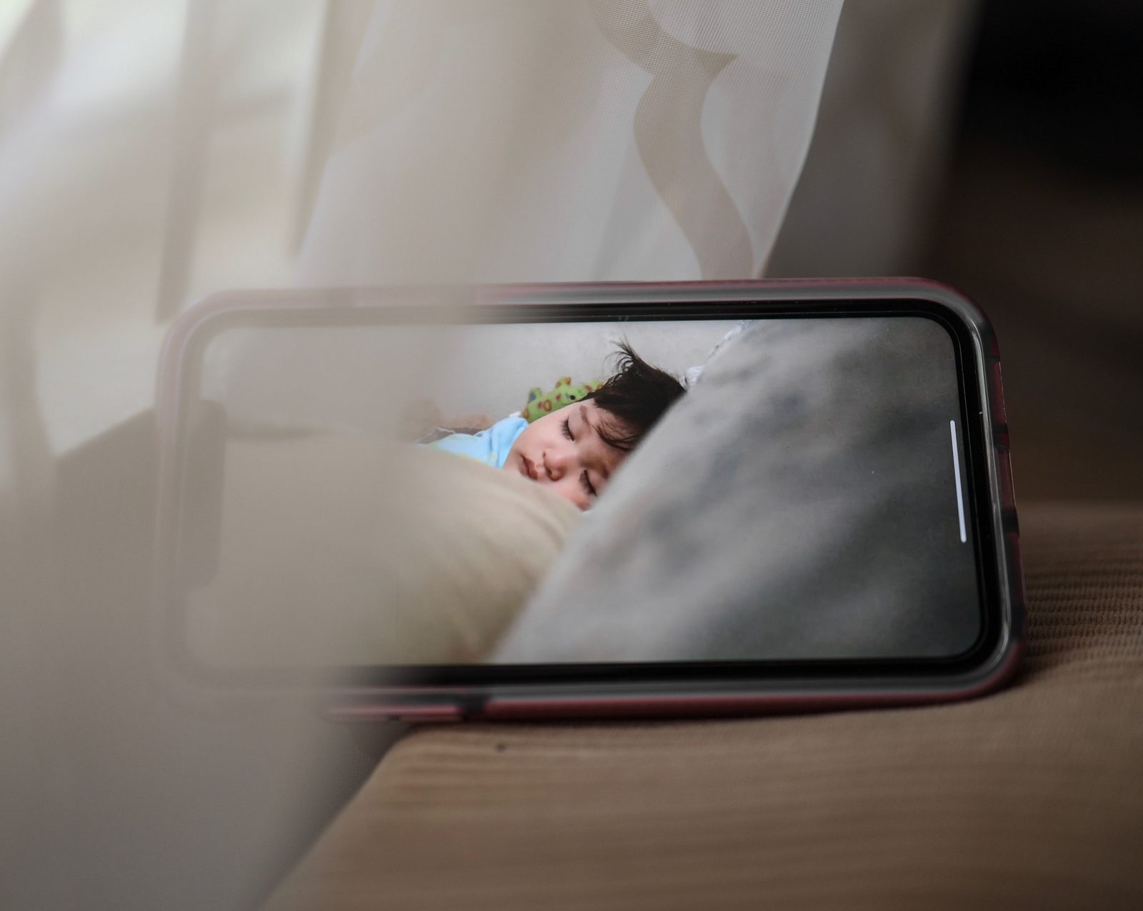 A smartphone screen showing a live view of a sleeping baby, like a baby monitor app