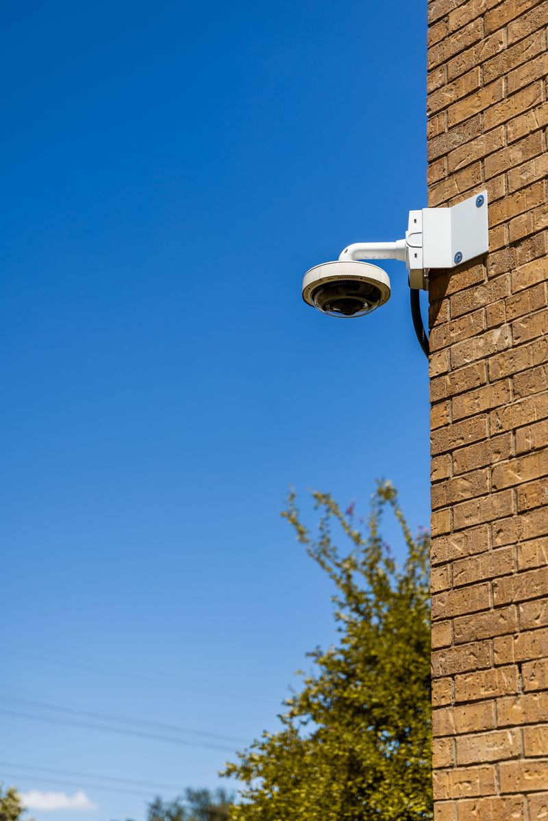 A wireless security camera mounted on the exterior brick wall of a house